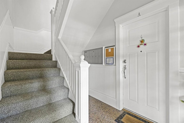 stairs featuring lofted ceiling, wainscoting, and mail area