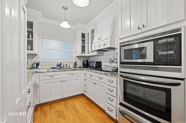 kitchen with stainless steel appliances, a sink, white cabinets, ornamental molding, and tasteful backsplash