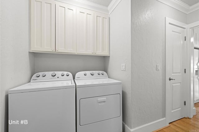 clothes washing area with light wood finished floors, cabinet space, washer and clothes dryer, a textured wall, and ornamental molding