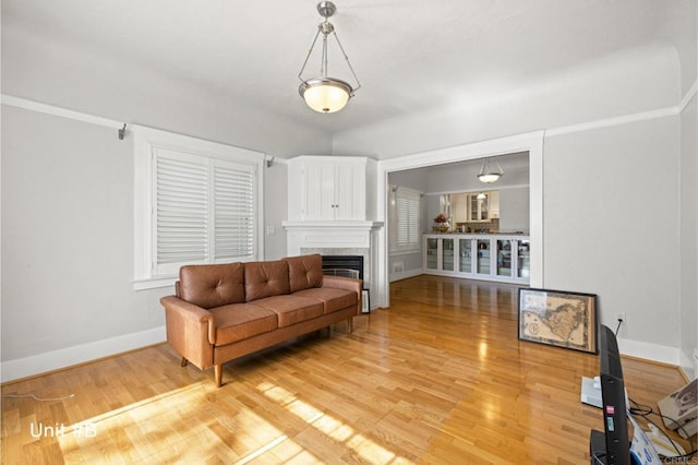 living area with light wood finished floors, a fireplace, and baseboards