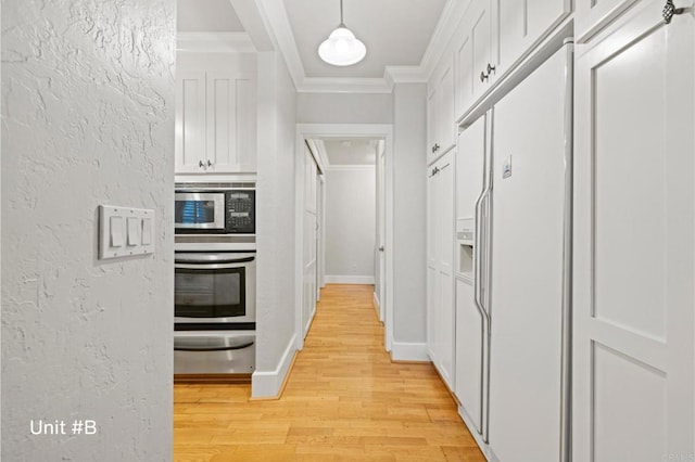 kitchen with stainless steel appliances, white cabinetry, a warming drawer, and ornamental molding