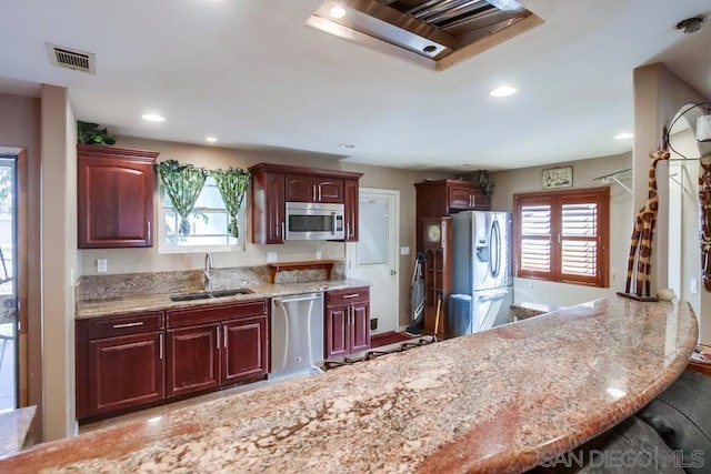 kitchen featuring light stone countertops, appliances with stainless steel finishes, a healthy amount of sunlight, and sink