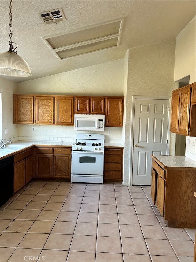 kitchen featuring light tile patterned floors, decorative light fixtures, vaulted ceiling, and white appliances