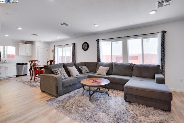 living room featuring light wood-type flooring, plenty of natural light, and sink