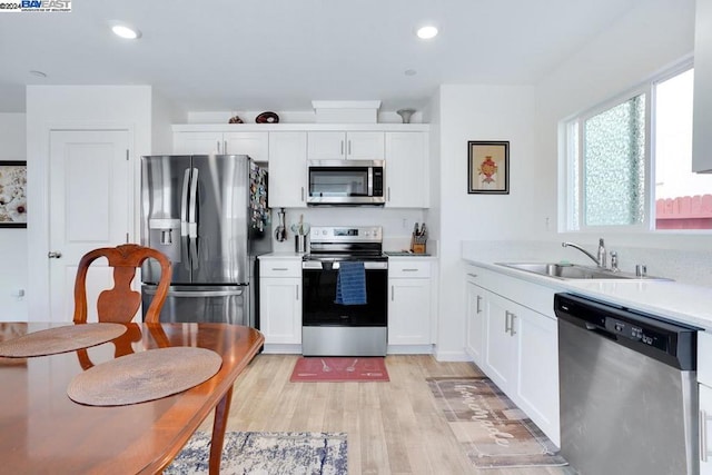 kitchen with white cabinetry, sink, light hardwood / wood-style flooring, and stainless steel appliances