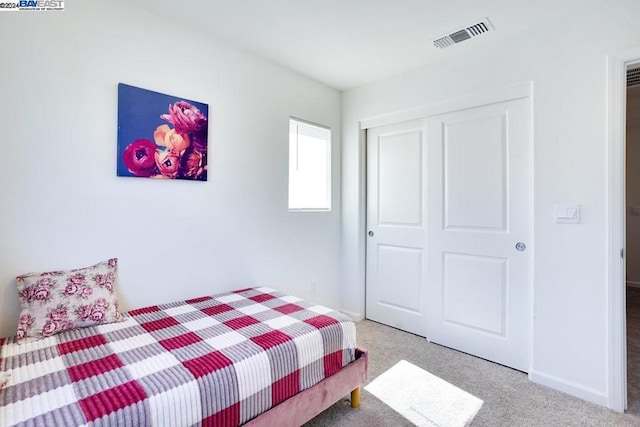 bedroom featuring light colored carpet and a closet