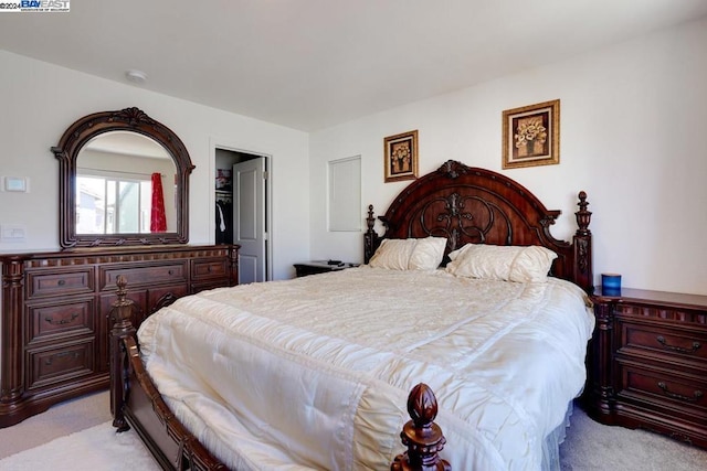 bedroom with light carpet, a walk in closet, and a closet