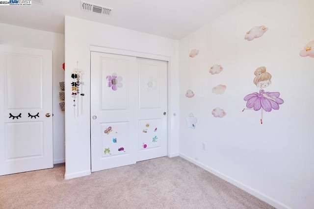 unfurnished bedroom featuring light carpet and a closet