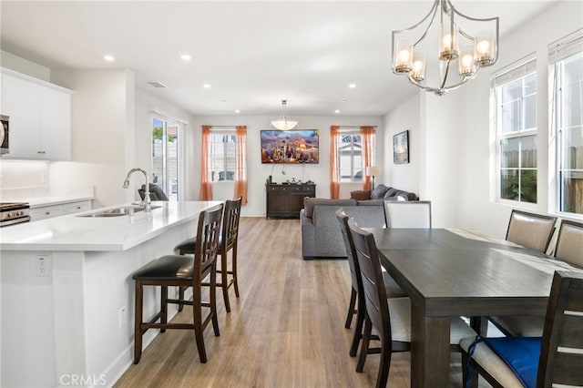 dining room with light hardwood / wood-style floors, sink, and a chandelier