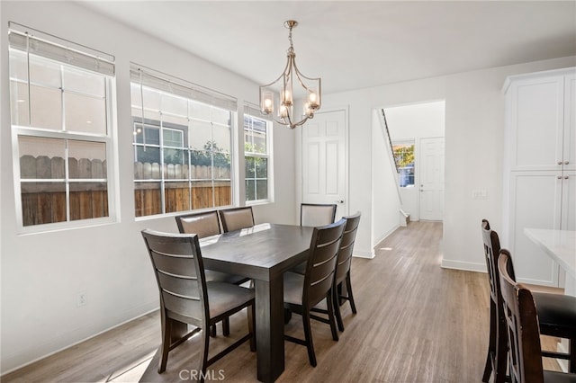 dining area with a notable chandelier, light hardwood / wood-style floors, and plenty of natural light