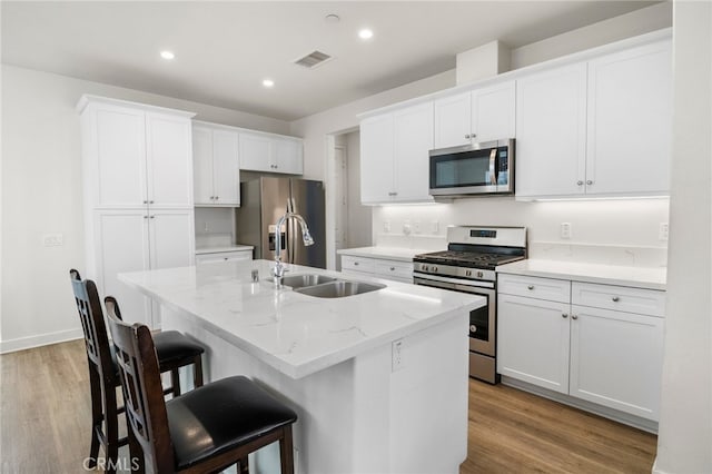 kitchen featuring white cabinets, a kitchen island with sink, stainless steel appliances, and sink