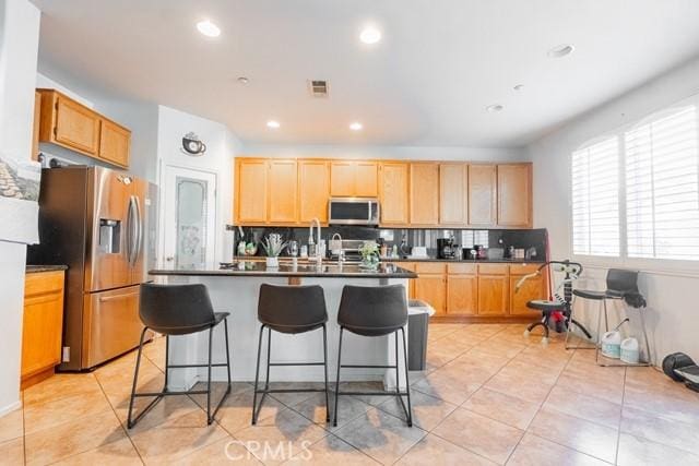 kitchen with decorative backsplash, a kitchen breakfast bar, stainless steel appliances, and light brown cabinetry