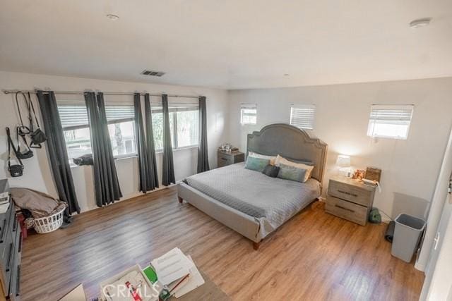 bedroom with light hardwood / wood-style floors and multiple windows