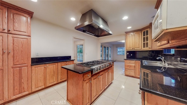 kitchen with light tile patterned floors, stainless steel gas cooktop, a center island, and ventilation hood