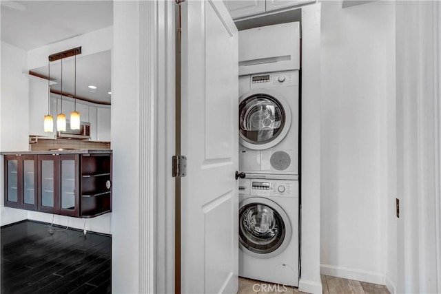 laundry room featuring hardwood / wood-style floors and stacked washer / drying machine