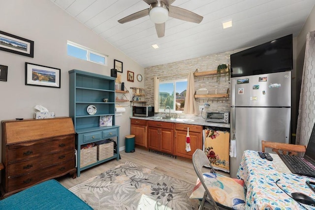 kitchen with ceiling fan, appliances with stainless steel finishes, vaulted ceiling, light hardwood / wood-style flooring, and sink