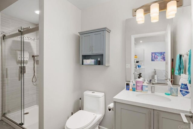 bathroom with toilet, vanity, and a shower with door