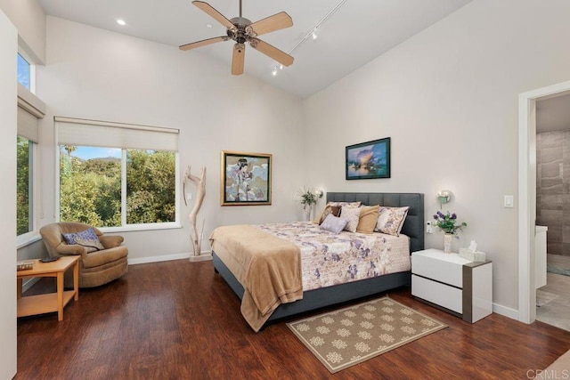 bedroom featuring rail lighting, ceiling fan, dark hardwood / wood-style floors, ensuite bath, and high vaulted ceiling