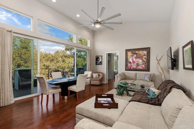 living room with ceiling fan, a high ceiling, and dark hardwood / wood-style floors