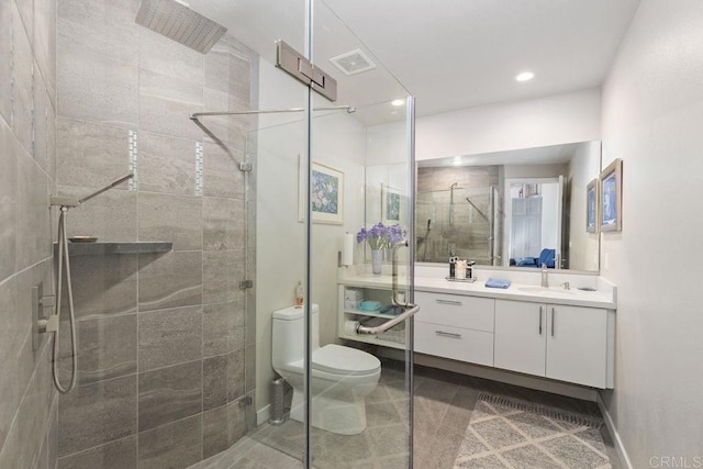 bathroom with toilet, vanity, tile patterned flooring, and tiled shower