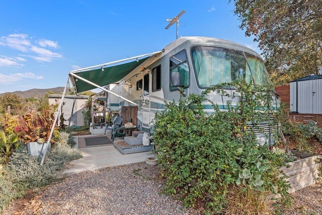 exterior space with a mountain view, a storage unit, and a patio