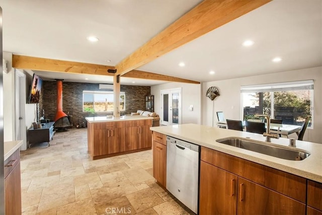 kitchen featuring a wood stove, a center island, dishwasher, sink, and beamed ceiling