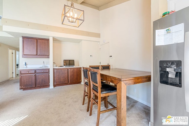 kitchen featuring an inviting chandelier, light colored carpet, decorative light fixtures, and stainless steel fridge