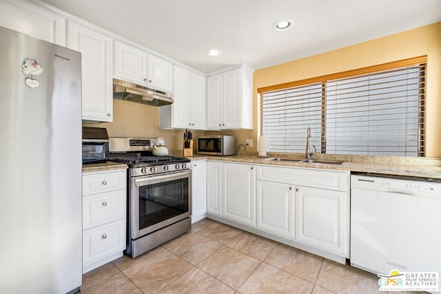 kitchen with light stone counters, white cabinets, light tile patterned floors, sink, and appliances with stainless steel finishes