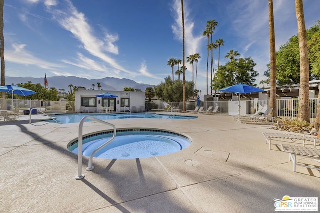 view of pool with a mountain view, a patio, and a hot tub