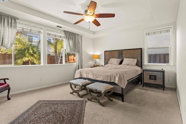 bedroom with a tray ceiling, ceiling fan, and light colored carpet