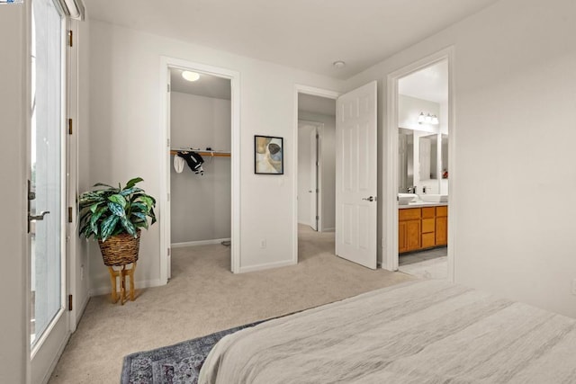 carpeted bedroom with a closet, ensuite bathroom, and a spacious closet