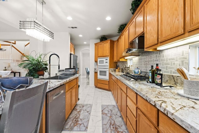 kitchen featuring sink, decorative light fixtures, backsplash, stainless steel appliances, and light stone countertops