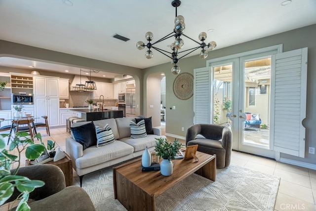 tiled living room featuring french doors, sink, and a chandelier