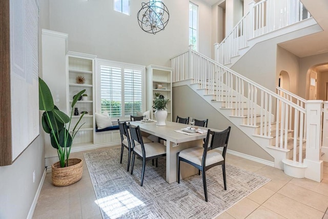 tiled dining space featuring a high ceiling and an inviting chandelier