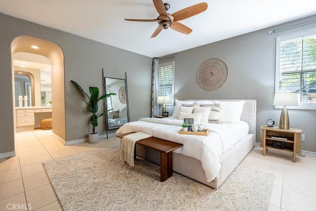 bedroom with light tile patterned floors, ensuite bathroom, and ceiling fan