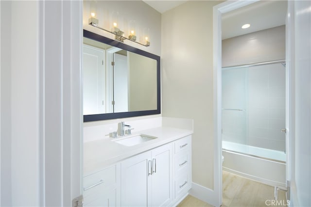 bathroom featuring hardwood / wood-style flooring, vanity, and bath / shower combo with glass door