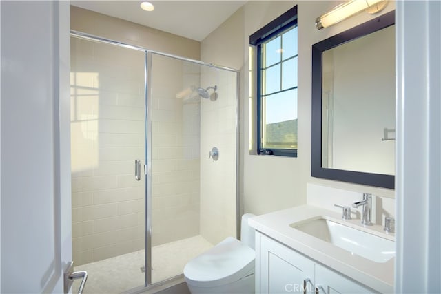 bathroom featuring vanity, toilet, and a shower with door