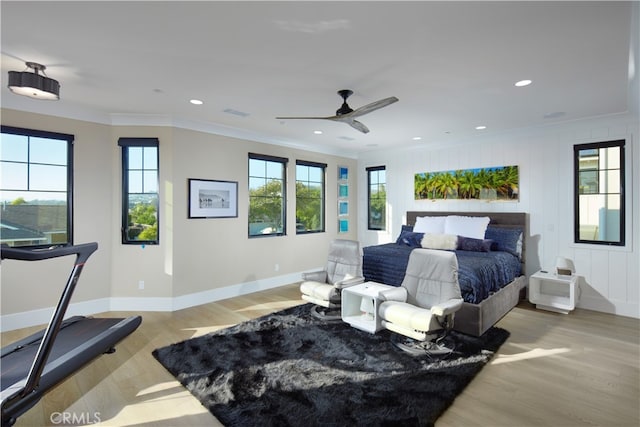 bedroom featuring crown molding, light hardwood / wood-style floors, wood walls, and ceiling fan