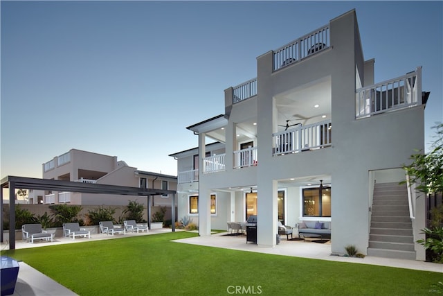 back of house with a balcony, a patio, outdoor lounge area, and a lawn