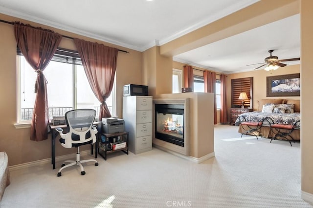 home office with a multi sided fireplace, ornamental molding, ceiling fan, and light colored carpet