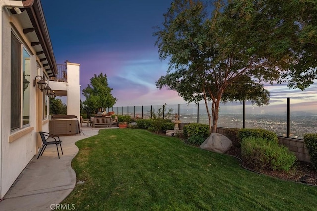 yard at dusk featuring a hot tub and a patio