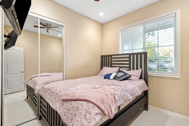 bedroom featuring ceiling fan, a closet, and light carpet