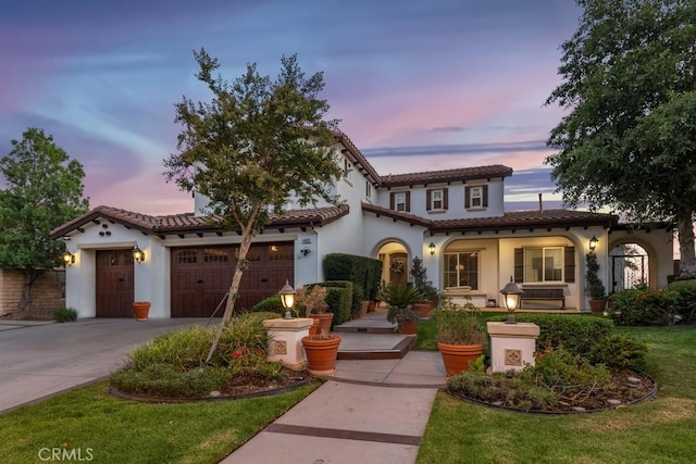 mediterranean / spanish house with a lawn and a garage