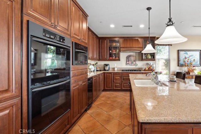 kitchen featuring sink, double wall oven, light stone countertops, hanging light fixtures, and premium range hood