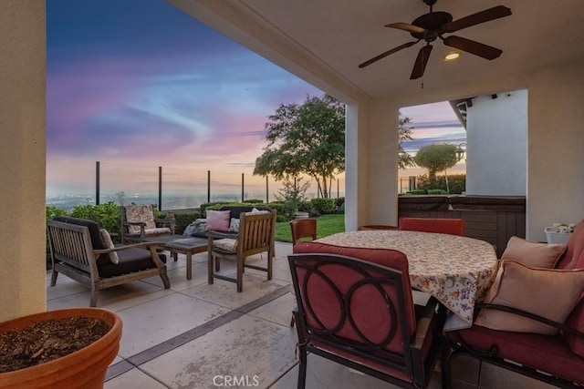 patio terrace at dusk featuring ceiling fan, a hot tub, and an outdoor hangout area