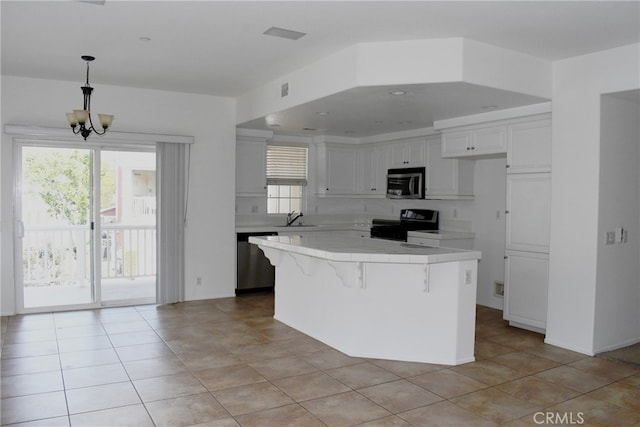 kitchen with a center island, sink, a notable chandelier, white cabinets, and appliances with stainless steel finishes