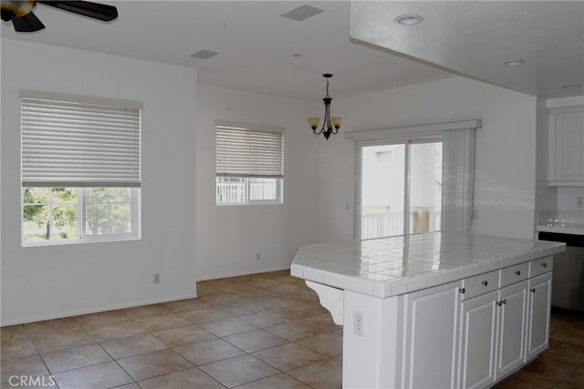 kitchen with a kitchen island, plenty of natural light, white cabinetry, and tile countertops