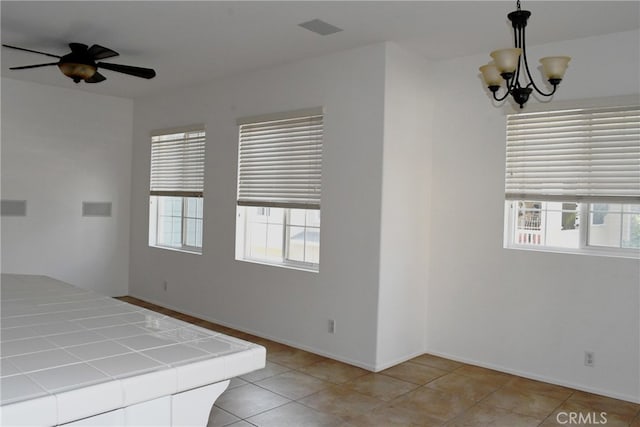 interior space with a notable chandelier, light tile patterned floors, and multiple windows