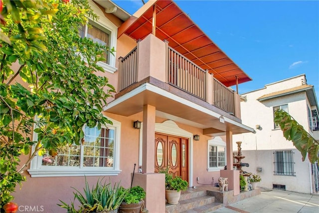 view of exterior entry with a balcony