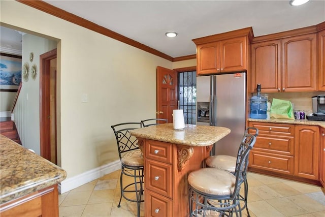 kitchen with a breakfast bar, light stone countertops, ornamental molding, a kitchen island, and stainless steel fridge with ice dispenser